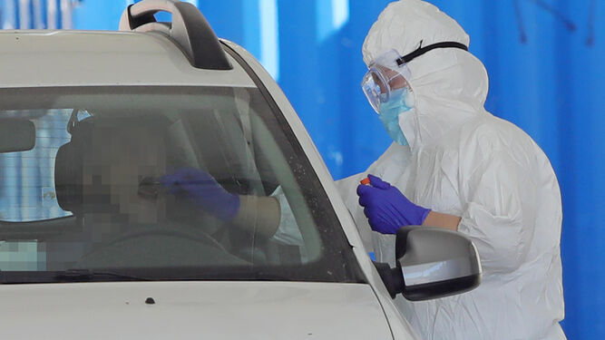 Una sanitaria realiza la prueba PCR a una persona en el interior de su coche.