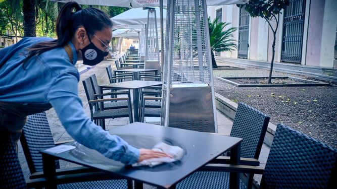 Una camarera desinfecta una de las mesas de la terraza, en la plaza de Mina.
