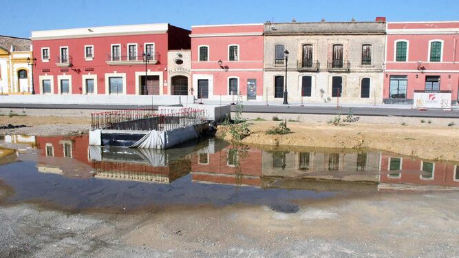 Los edificios de Pozos Dulces se reflejan en el agua de las últimas lluvias, entre ellos el Casino Bahía de Cádiz, que aguarda el fin de la obra para su traslado.