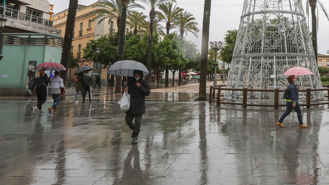 Imagen de la plaza del Arenal, con algunos viandantes bajo la lluvia este domingo.