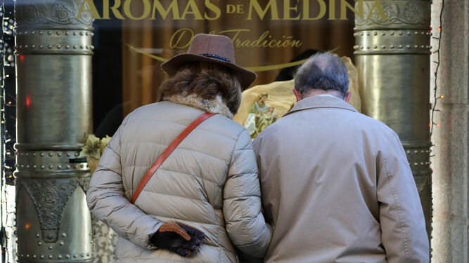 Dos personas caminando abrigadas por una calle del centro de Jerez