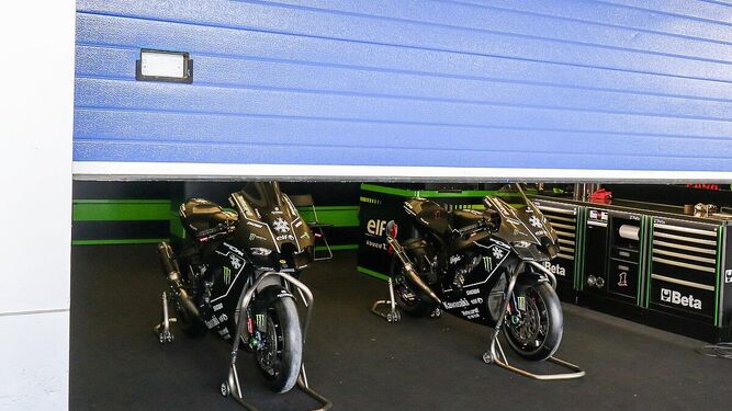 Las motos del Kawasaki Racing Team, en el box con la persiana medio bajada.