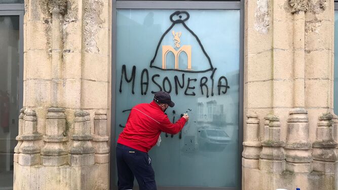 Trabajos de limpieza de la pintada realizada en uno de los ventanales acristalados de Las Covachas.