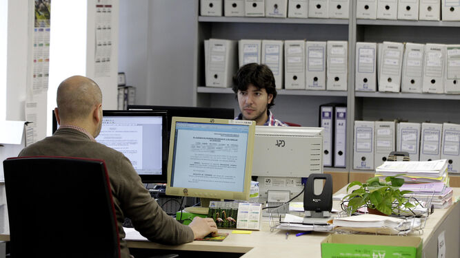 Dos funcionarios examinando unos documentos en sus ordenadores en una imagen retrospectiva.