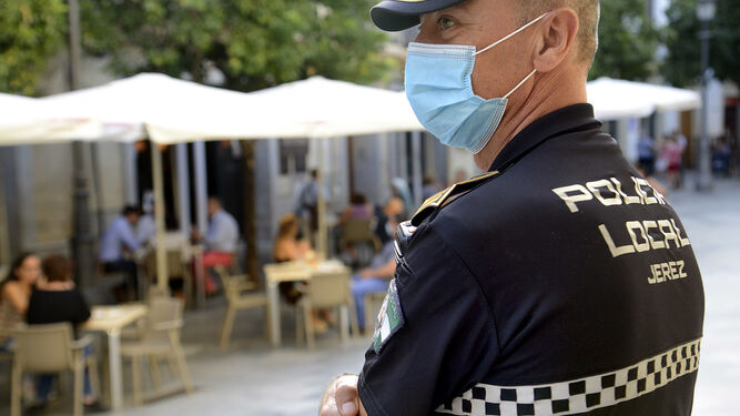 Un policía local junto a una terraza antes del actual cierre de la actividad no esencial en Jerez.