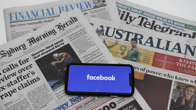 Un móvil con el logo de Facebook sobre varios periódicos australianos.