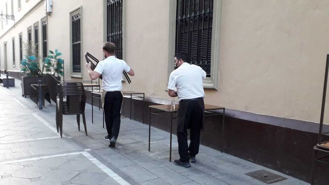 Camareros recogiendo una terraza en un establecimiento hostelero.