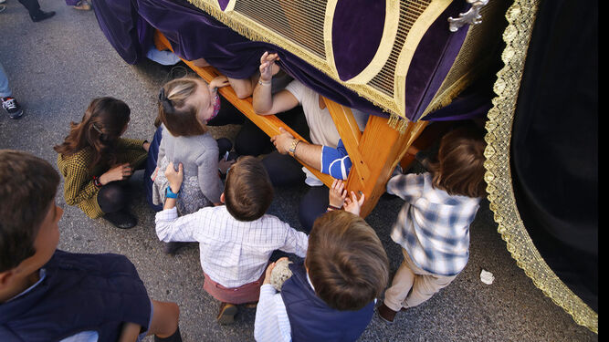 Costaleros del palio de la Virgen de la O conversan con los pequeños que presencian la procesion.
