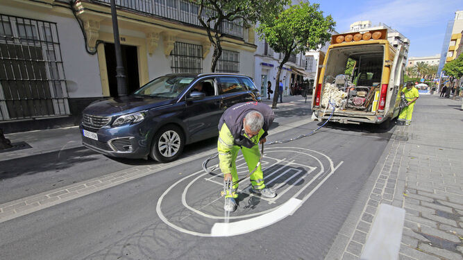 Un turismo circula por el carril bici mientras trabajadores pintan las señales horizontales en calle Corredera.