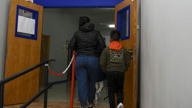 Dos niños abandonando una sala, acompañados por un adulto.