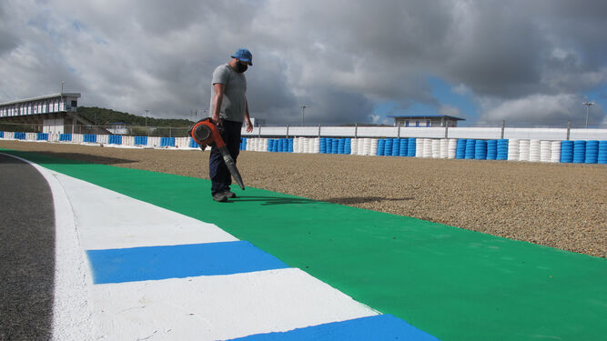 Un operario seca una zona verde recién pintada.
