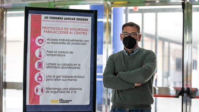 Pedro Fernández, coordinador covid del IES Fernando Aguilar Quignon de Cádiz, junto a un cartel con las medidas adoptadas en este centro.