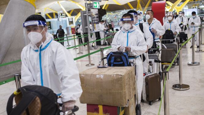 Trabajadores procedentes de China con trajes de protección ayer en la terminal T4 del aeropuerto de Madrid-Barajas.