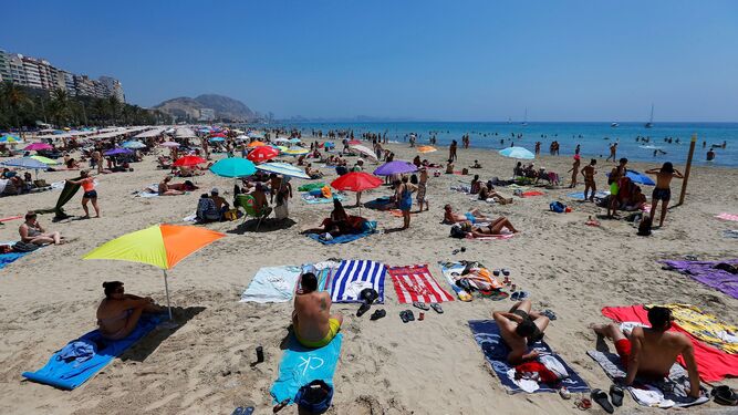 Turistas disfrutan de un soleado día en la playa del Postiguet, en Alicante.