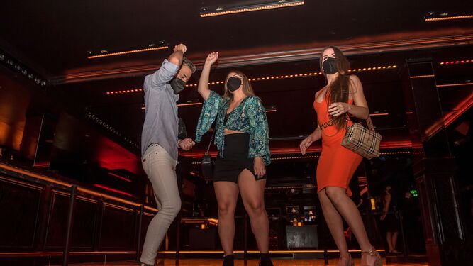 Varias personas bailan en el interior de una discoteca.
