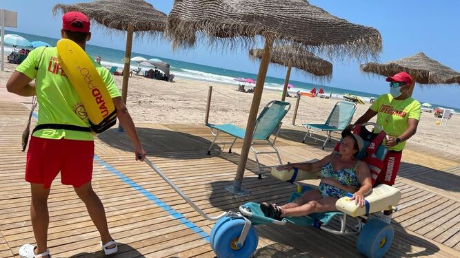 El personal del módulo de accesibilidad 5 Estrellas de la playa de Camposoto atiende a una usuaria.