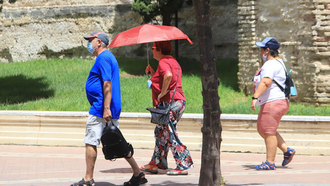Una mujer, con un paragüas para protegerse del sol en la Alameda Vieja.