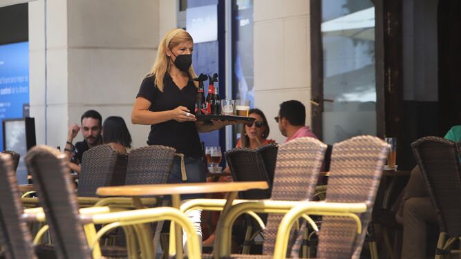 Una camarera con una bandeja de bebidas en un bar de la zona de Hipercor.