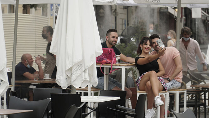 Varios jóvenes disfrutan de la terraza de un bar en Sevilla.