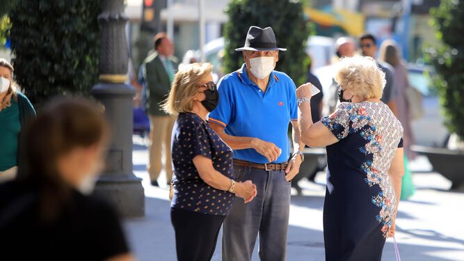 Ciudadanos con la mascarilla puesta conversan en una calle del centro.