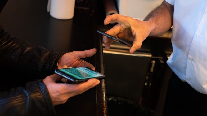Un hombre escanea con su móvil el certificado Covid de otro usuario.