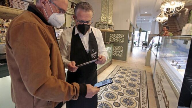 Un camarero comprueba el pasaporte covid de un cliente en un establecimiento hostelero de Jerez.