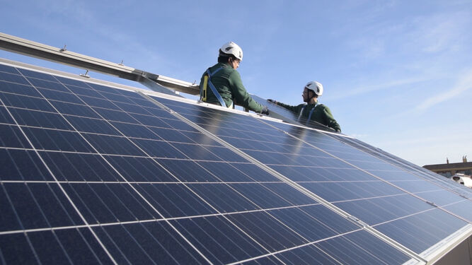 Unos operarios instalan unas placas solares.