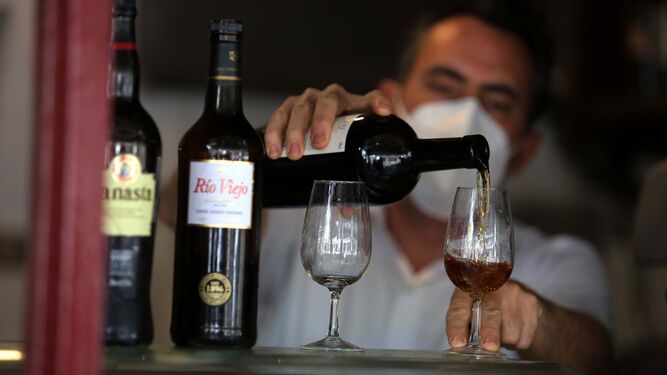 Un camarero sirve unas copas de vino de Jerez.