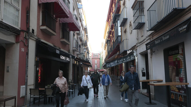 Varios turistas caminan por una céntrica calle repleta de bares.