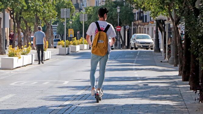 Un joven en patinete eléctrico por una ciudad.