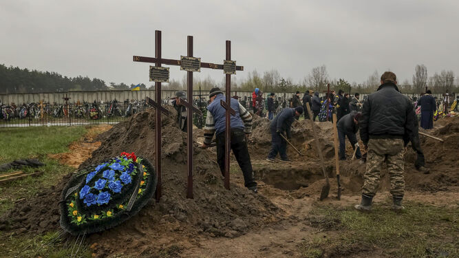 Varias personas entierran un cuerpo en el cementerio de Bucha, en Ucrania