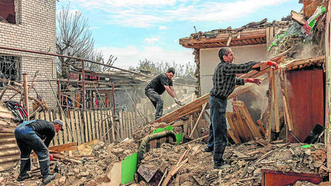 Unos hombres reconstruyen sus viviendas destrozadas por los bombardeos en la localidad ucraniana de Zaporiya.