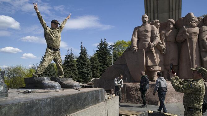 Unos soldados se hacen fotos sobre las últimas piezas de una estatua conmemorativa entre Ucrania y Rusia en Kiev.