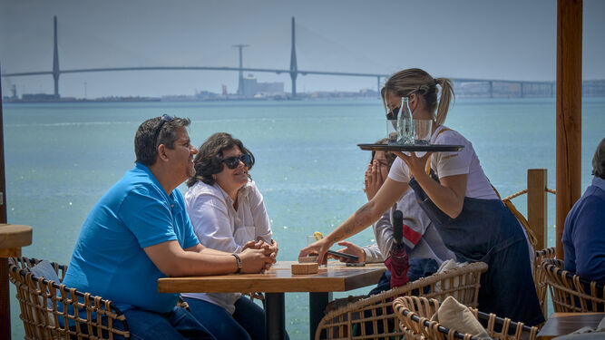 Una camarera atiende a unos clientes en una terraza en Puerto Sherry.