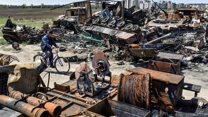 Un hombre pasa en bicicleta entre restos de vehículos militares en Bucha
