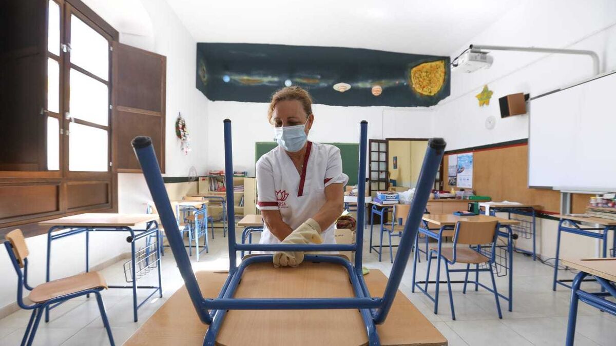 Una limpiadora prepara una clase en un colegio de Chiclana.