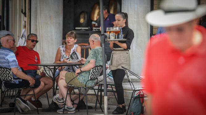 Una camarera atienda a unos turistas en la terraza de un bar del centro.