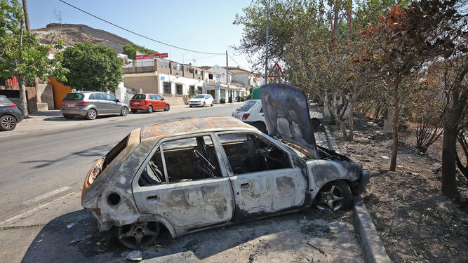 Calle principal de Lomopardo con el coche abandonado que acabó calcinado por las llamas.