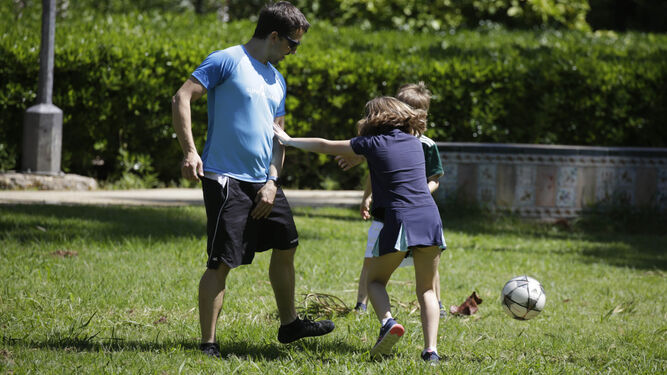 Un padre juega con sus hijos en un parque