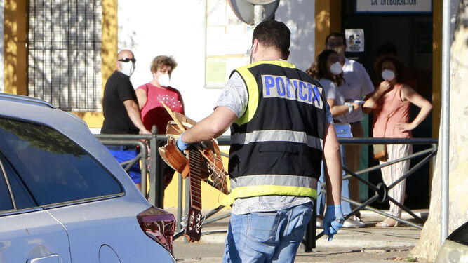 Un policía porta la guitarra con la que fue golpeada la víctima.
