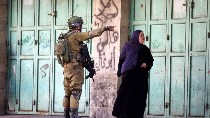 Un soldado israelí da indicaciones a una mujer palestina en Hebron.