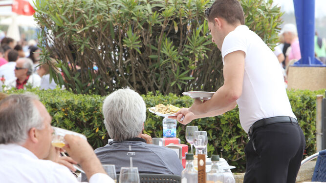 Un camarero atiende una de las terrazas de un restaurante de La Barrosa, en una imagen de archivo.