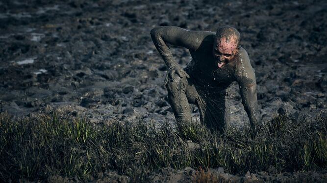 Uno de los participantes atraviesa el fango exhausto.