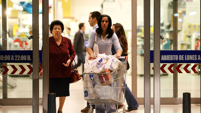 Una mujer sale de un supermercado con el carro de la compra