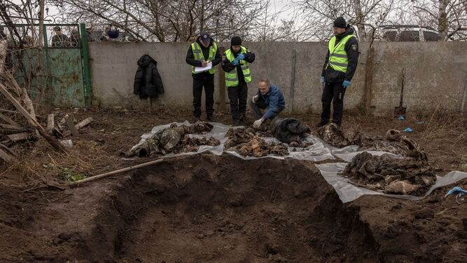 Un forense inspecciona los restos de seis cuerpos tras su exhumación de una fosa común en las afueras de Jerson.