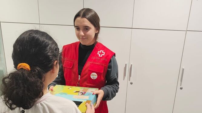 Una voluntaria de Cruz Roja entrega un juguetes a una niña.