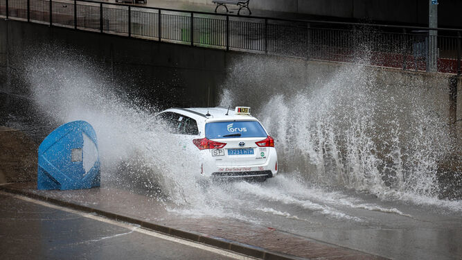 Un coche circula por el puente de la avenida La Pepa anegado por las fuertes lluvias de ayer por la mañana.