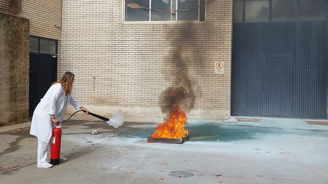 Una sanitaria del Hospital de Jerez sofoca un fuego durante el curso para saber manejar un extintor.