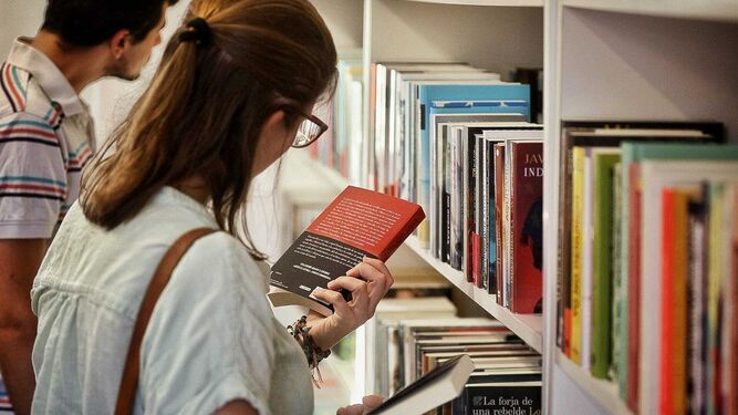 Una joven lee la sinopsis de un ejemplar durante la pasada Feria del Libro de Cádiz