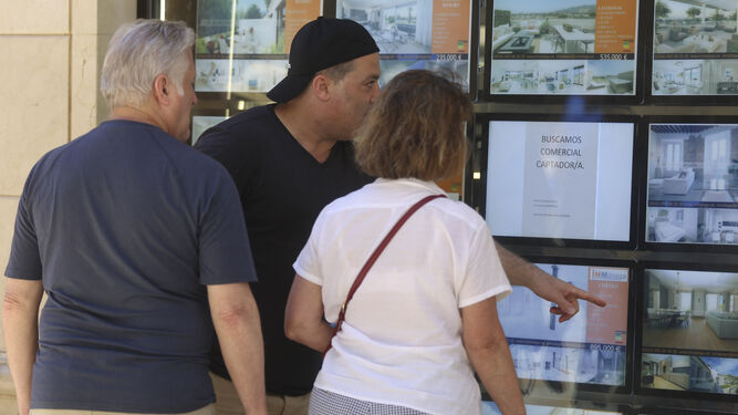 Un grupo de personas consulta el escaparate de una inmobiliaria.